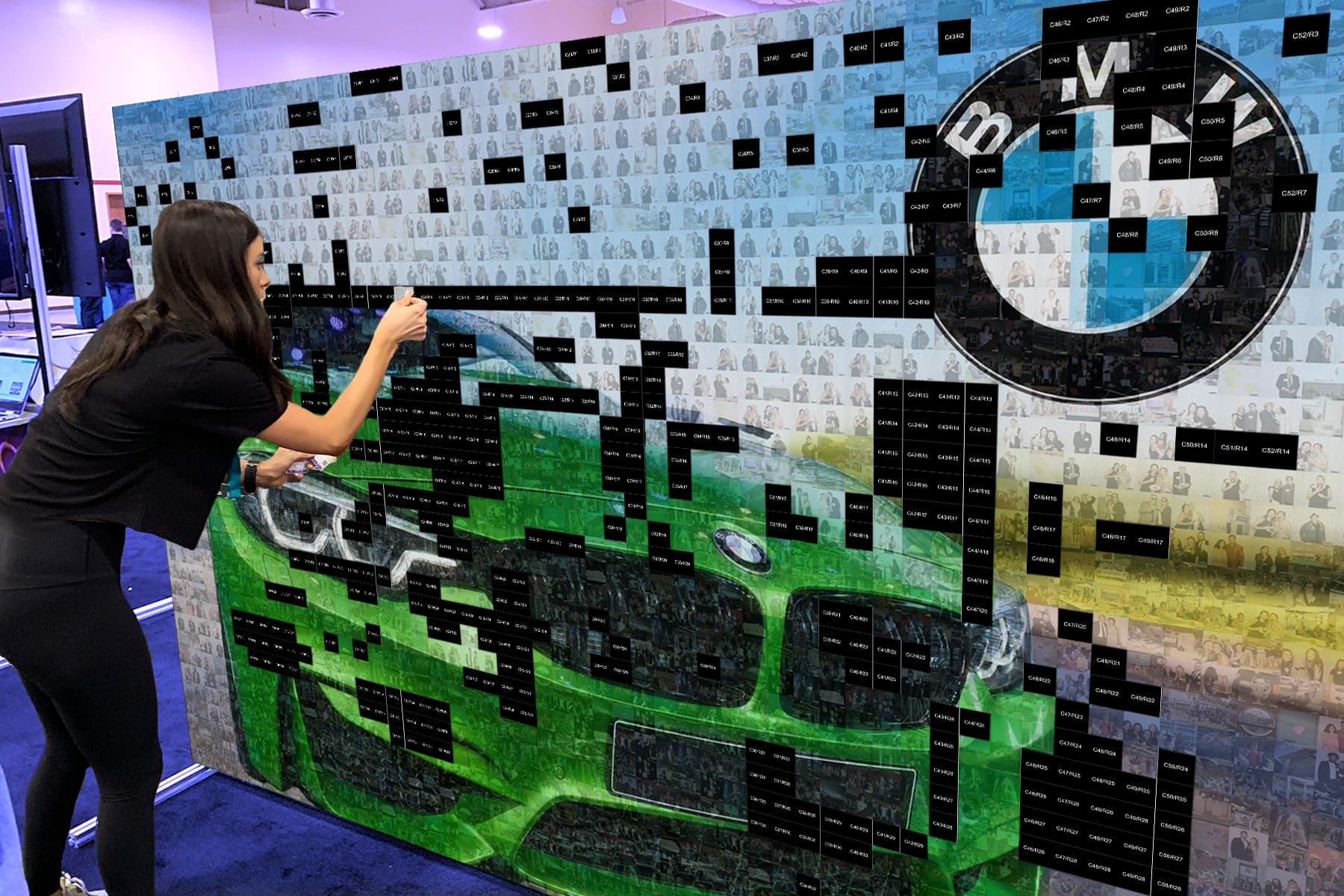 Young lady placing photo tiles on giant photo wall of BMW car and BMW logo as part of the final image.